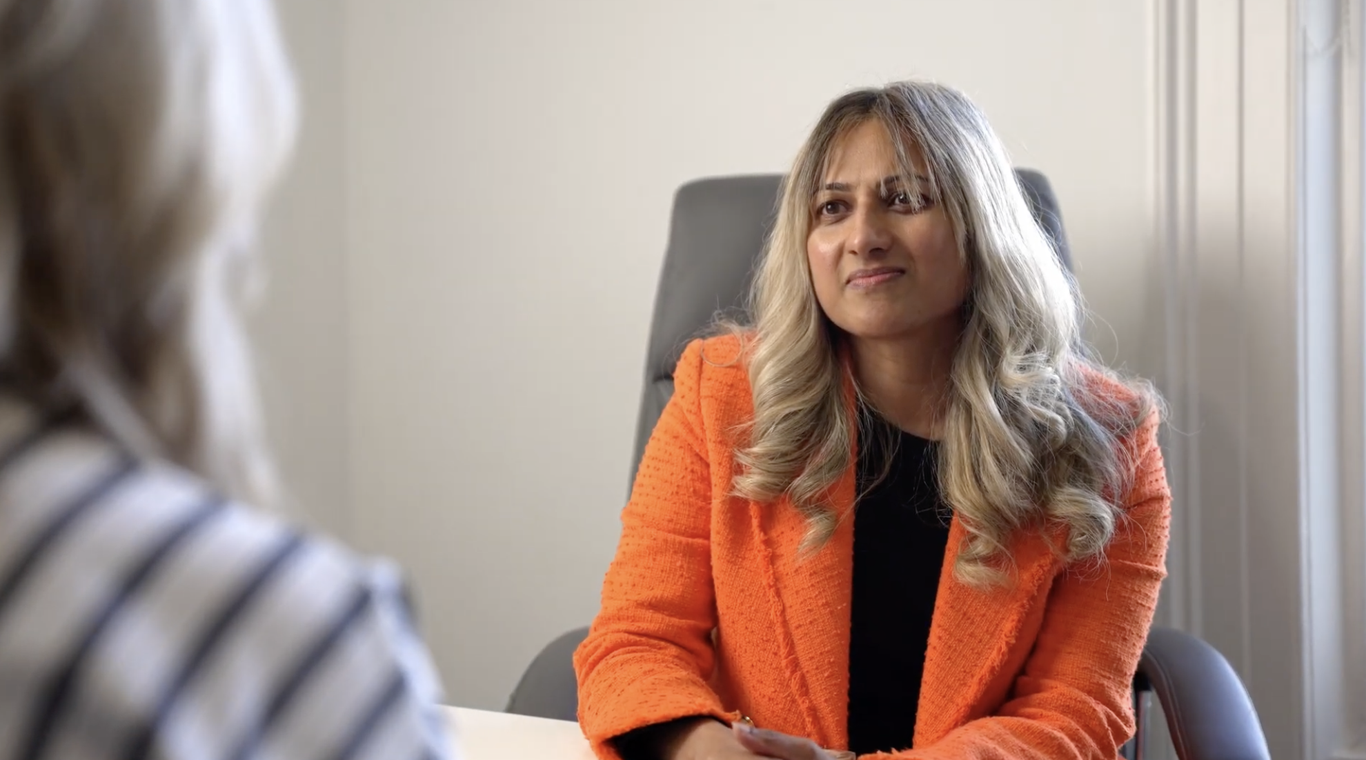 Dr Kallan sitting at a table, engaged in a conversation with a patient.