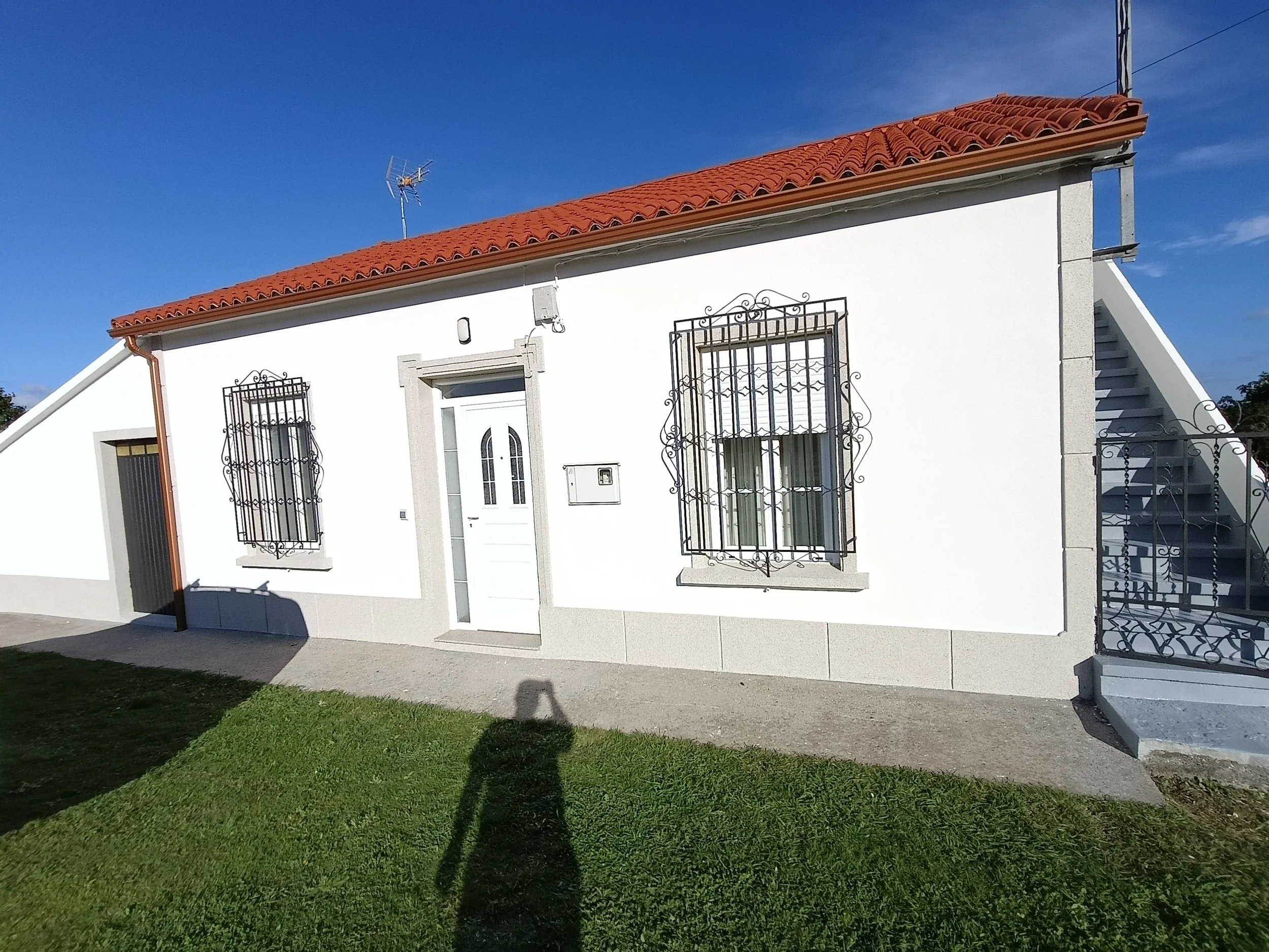 Casa blanca con tejado rojo y rejas en las ventanas. 