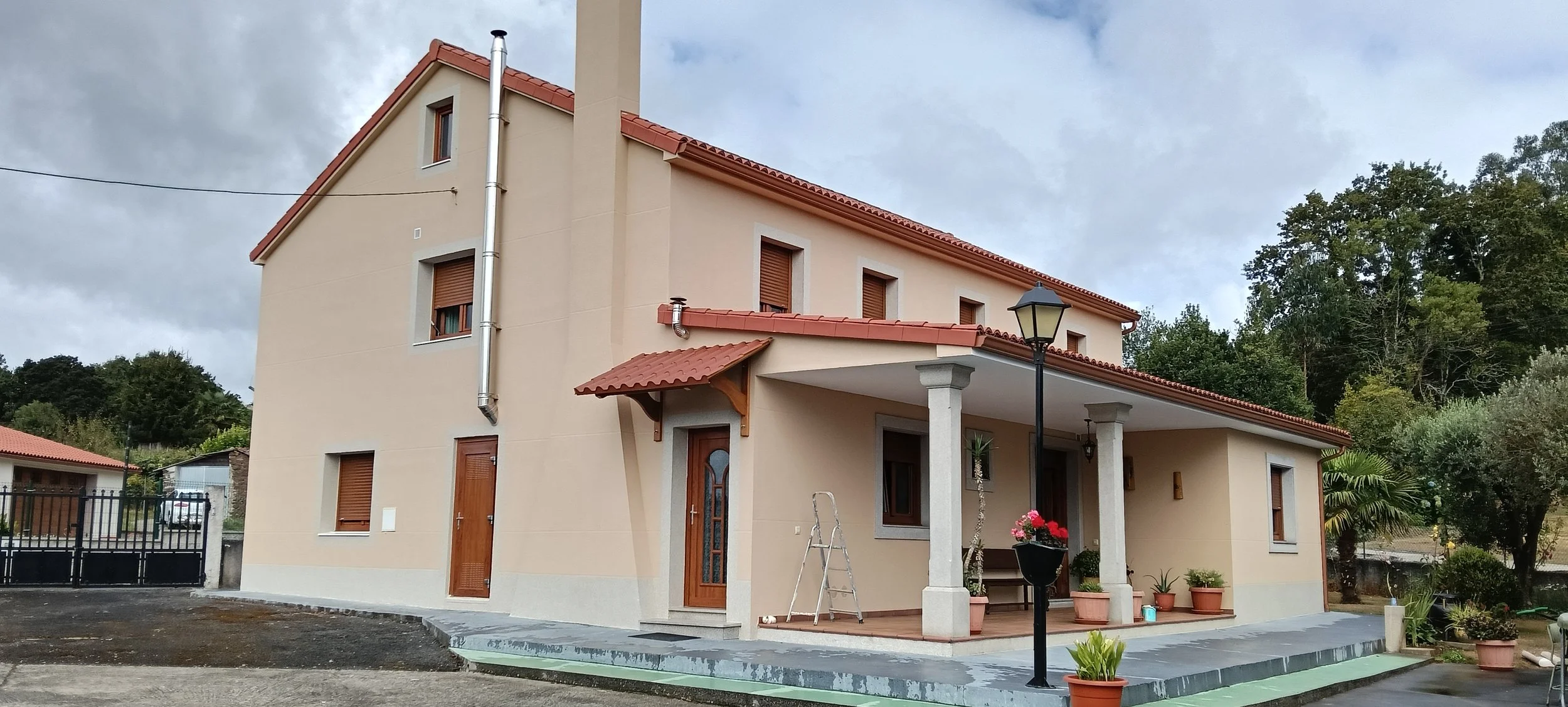Casa de planta alta color salmón con porche y tejado rojo.
