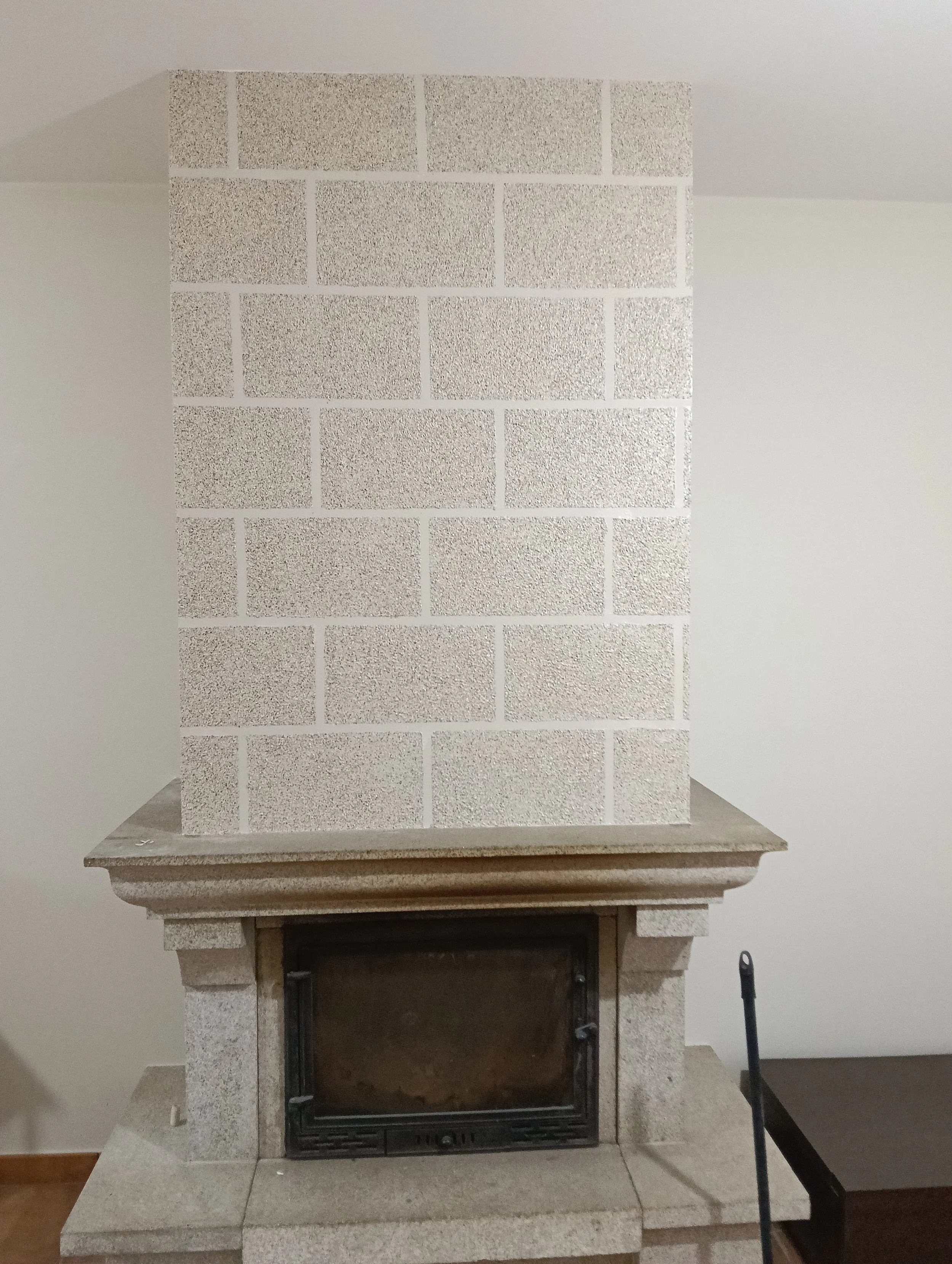 Chimenea que parece estar hecha de piedra y paredes de fondo blanco. 