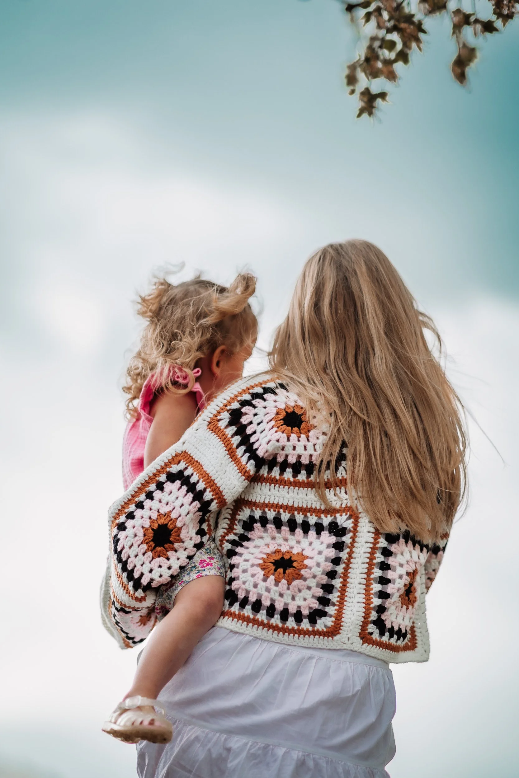 Mom and daughter standing under stormy clouds along Bobolink Trail during a family maternity session in Boulder, CO