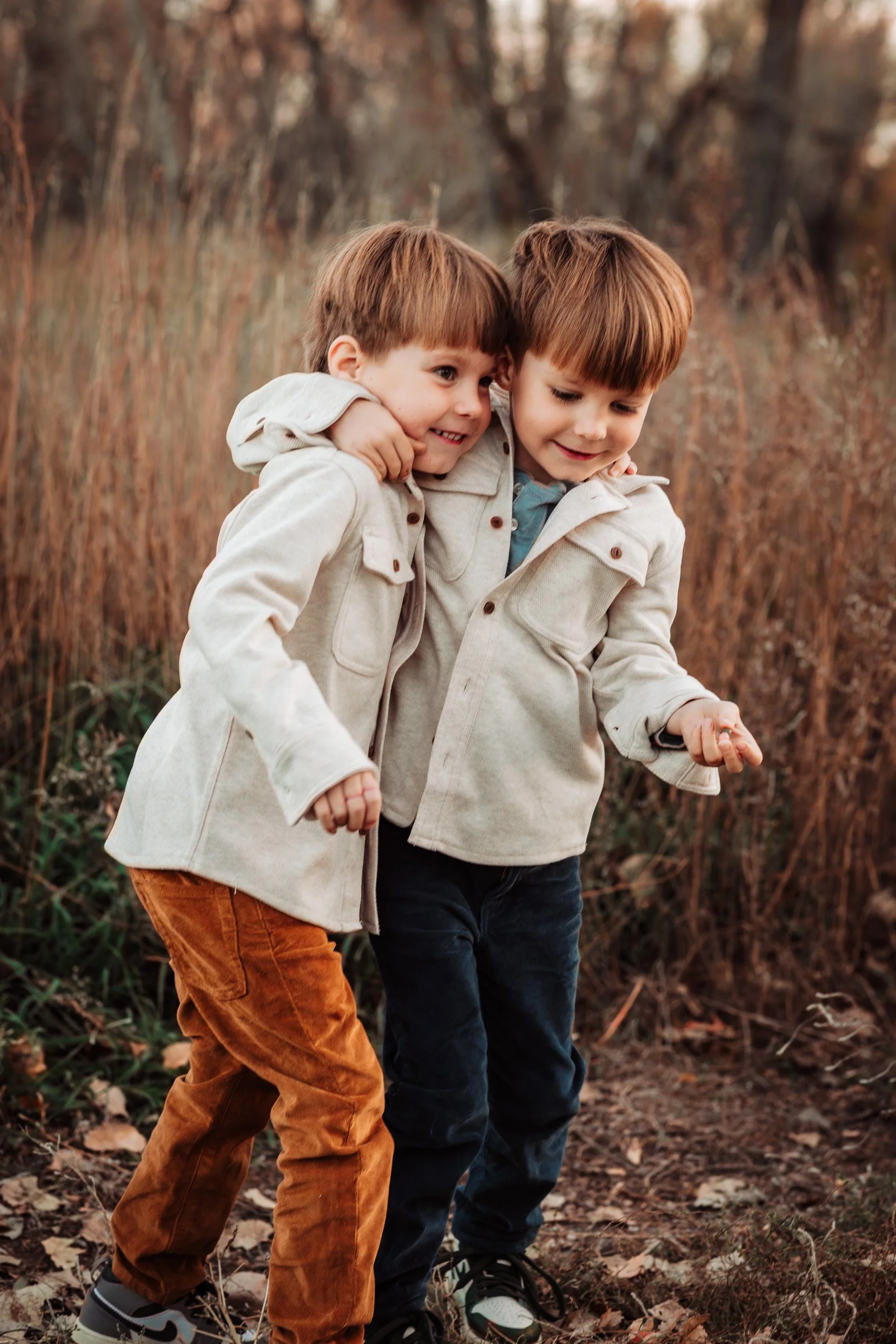 twin boys hugging and walking on path at golden hour