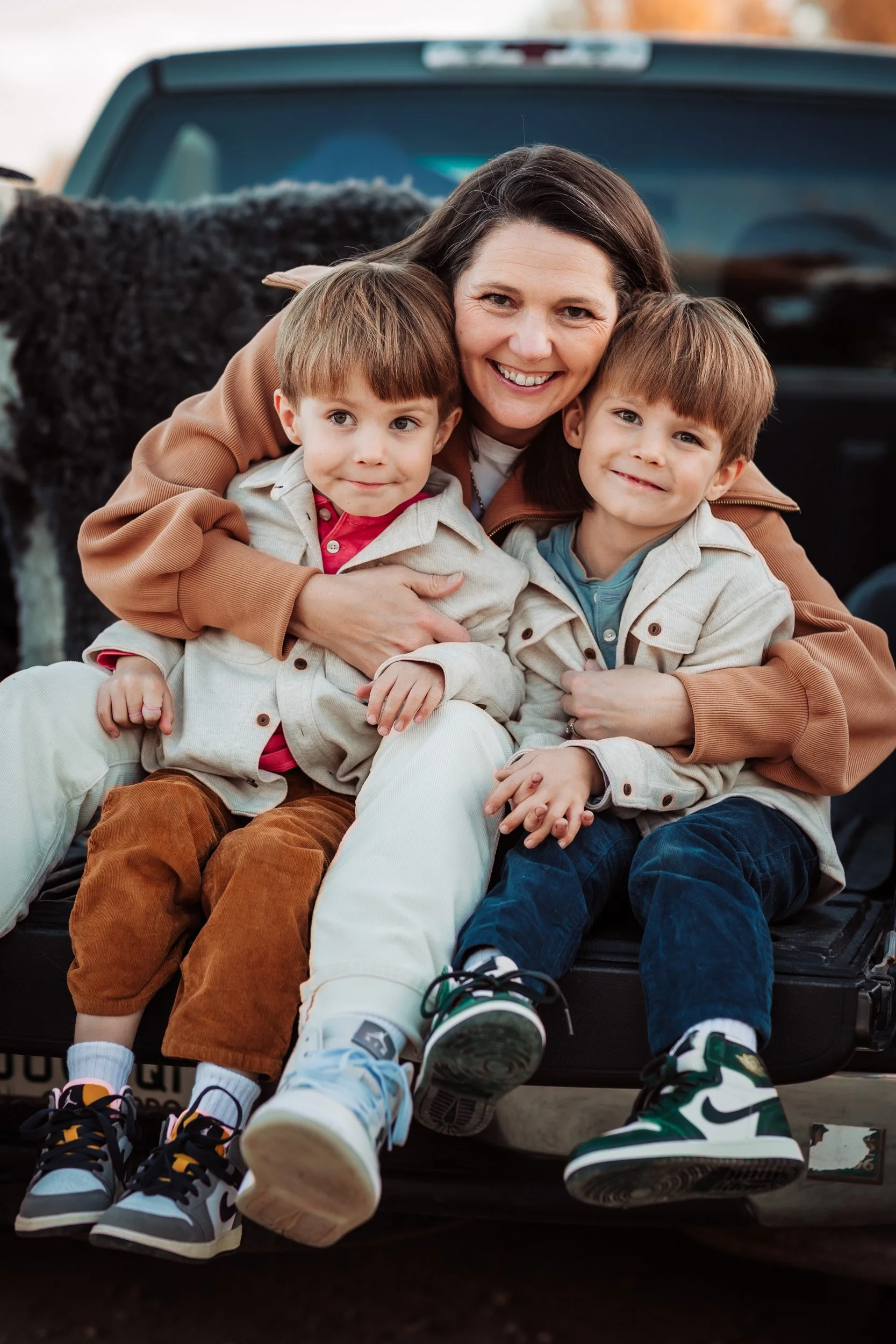 mom and twin sons getting cozy in truck bed during golden hour