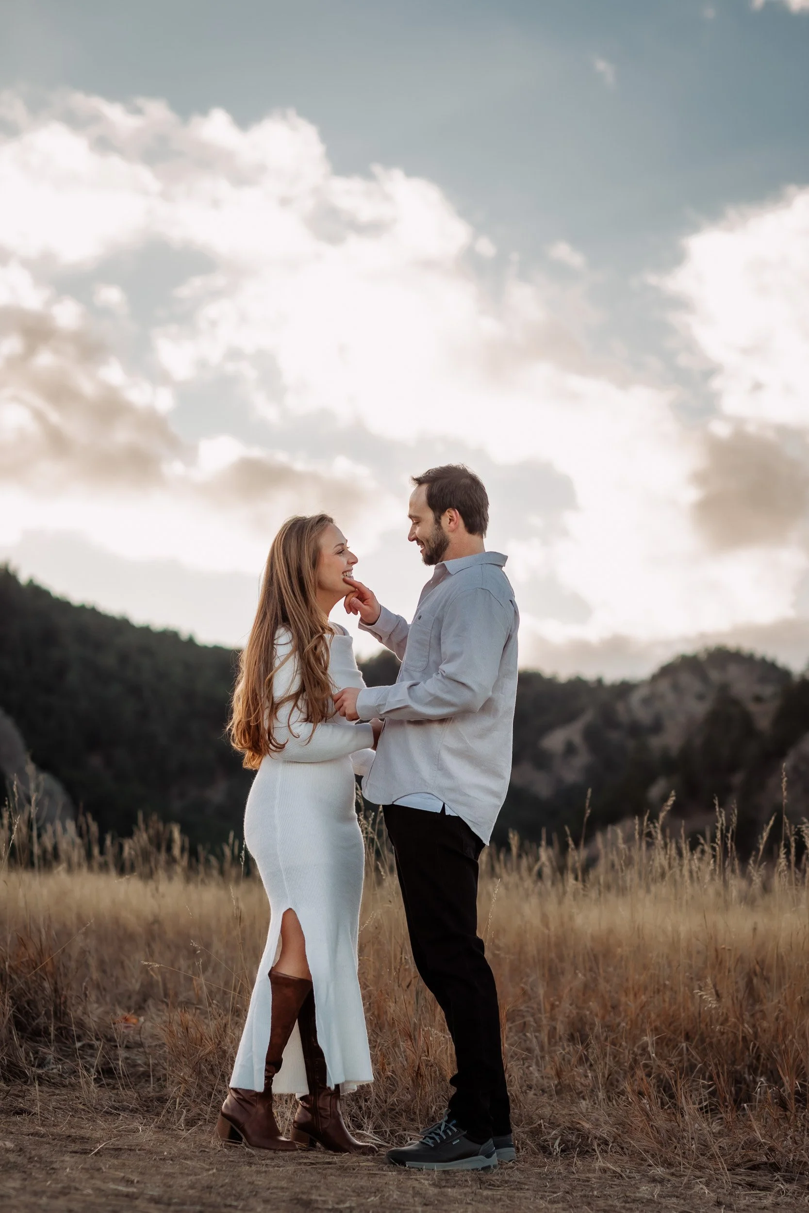 Candid engagement portrait of couple laughing with the Flatirons behind them in late fall