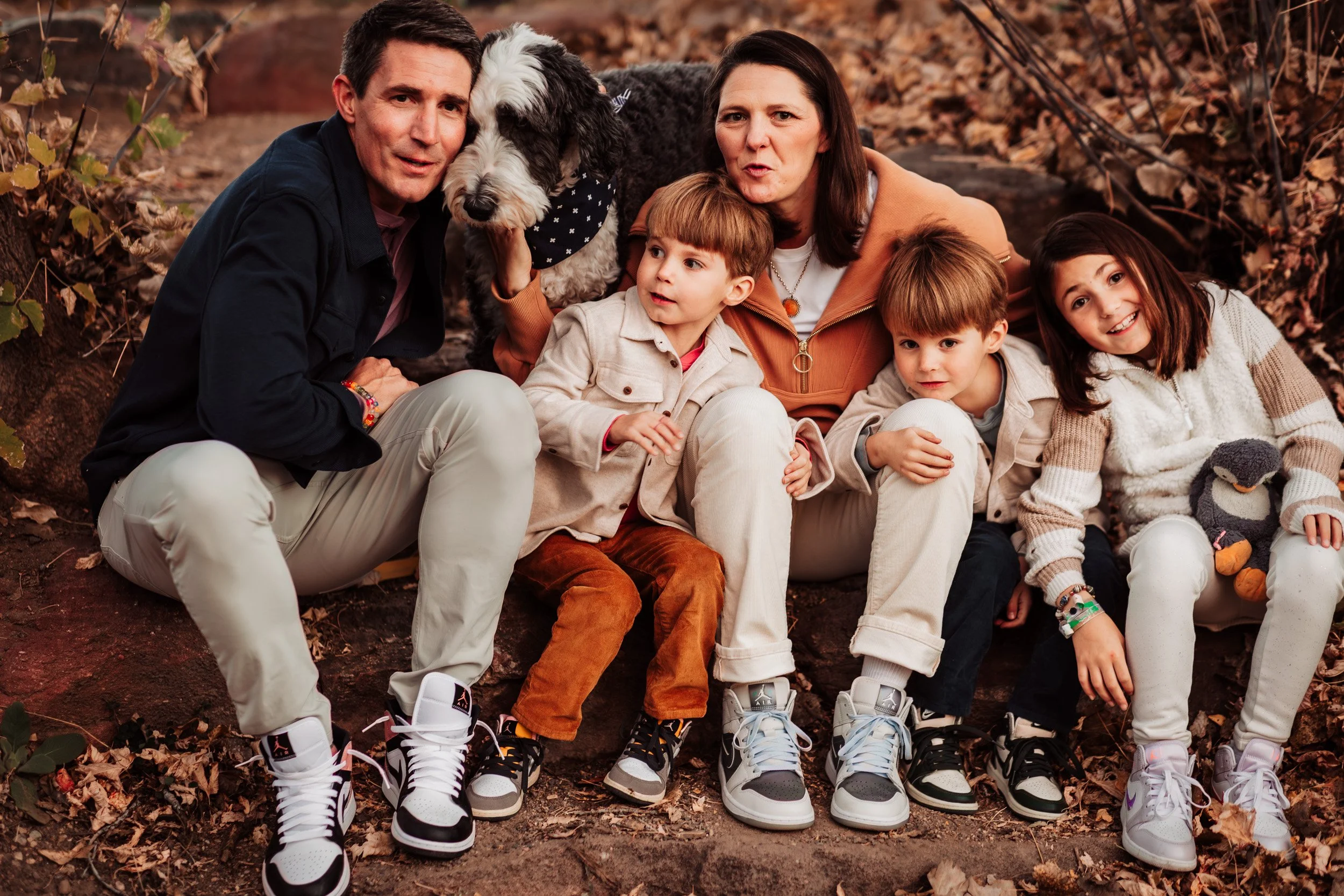 Playful family laughing together beside a creek at Bobolink Trail in October