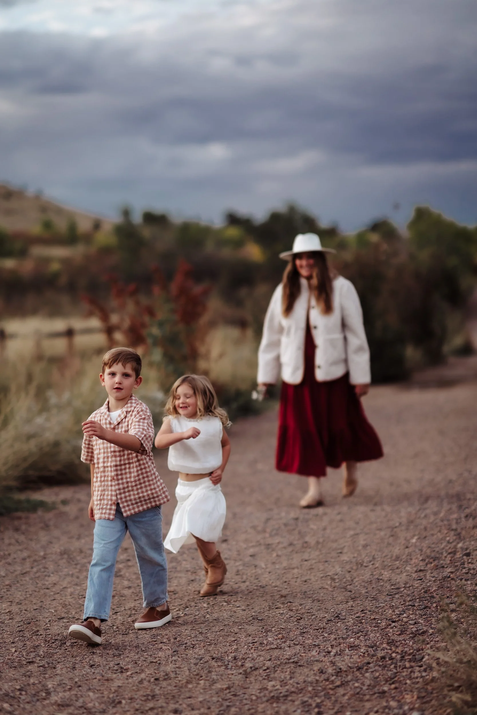 Mom wearing a white wide-brim hat and quilted jacket with kids at South Mesa Trailhead