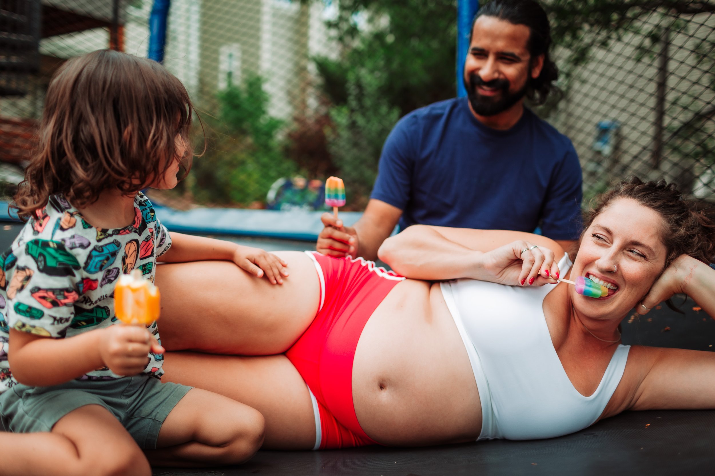 Expecting mother eating popsicles with her family during an at-home maternity session in Boulder