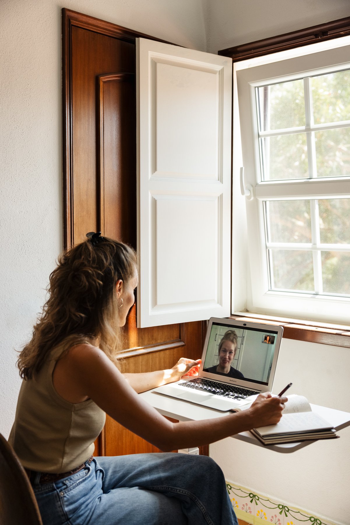 Frau führt ein Video-Meeting auf einem Laptop im Raum mit natürlichem Licht durch.