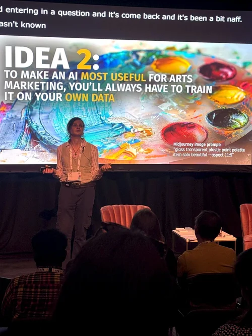A photograph of Jocelyn Burnham presenting at the Arts Marketing Association conference. She's discussing 5 Ideas About AI.