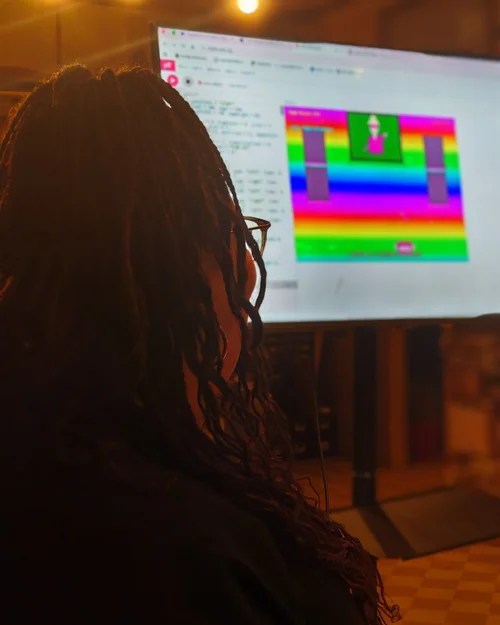 A workshop participant works on their game's code on a large screen