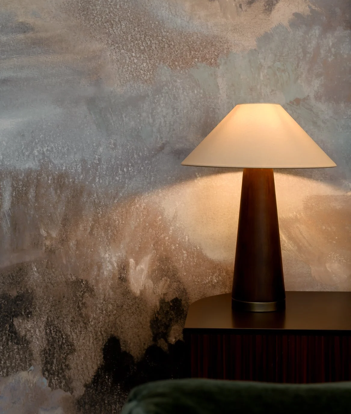 Warm table lamp and textured wall detail in a completed residential interior project.