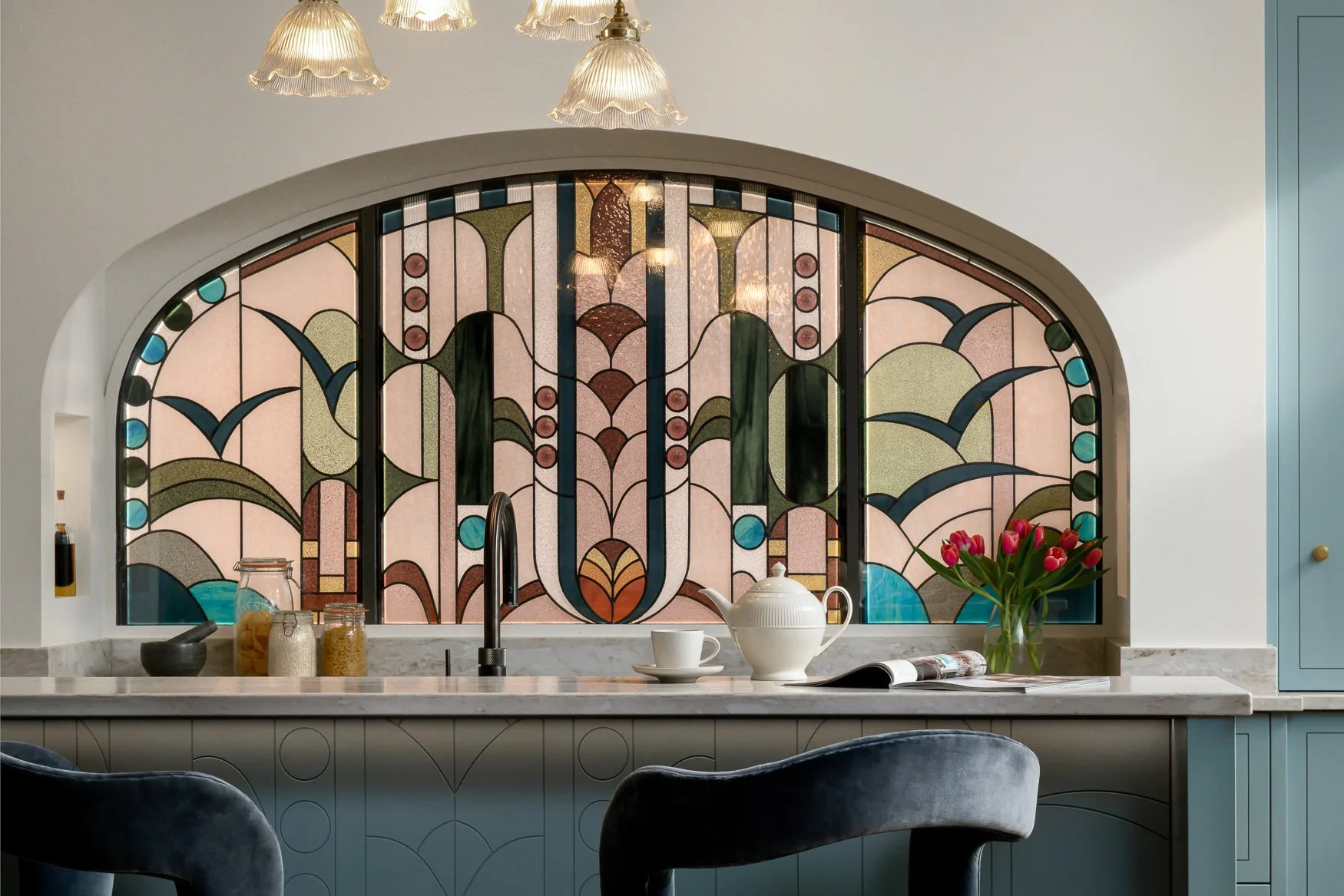 Close-up of stained glass splashback, marble worktop and styling details in a bespoke kitchen.