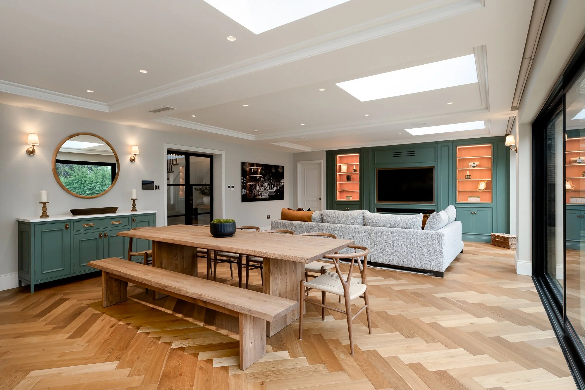 Interior architecture photograph of an open-plan residential living and dining space with rooflights, large glazing, herringbone timber flooring and fitted media joinery. City of London