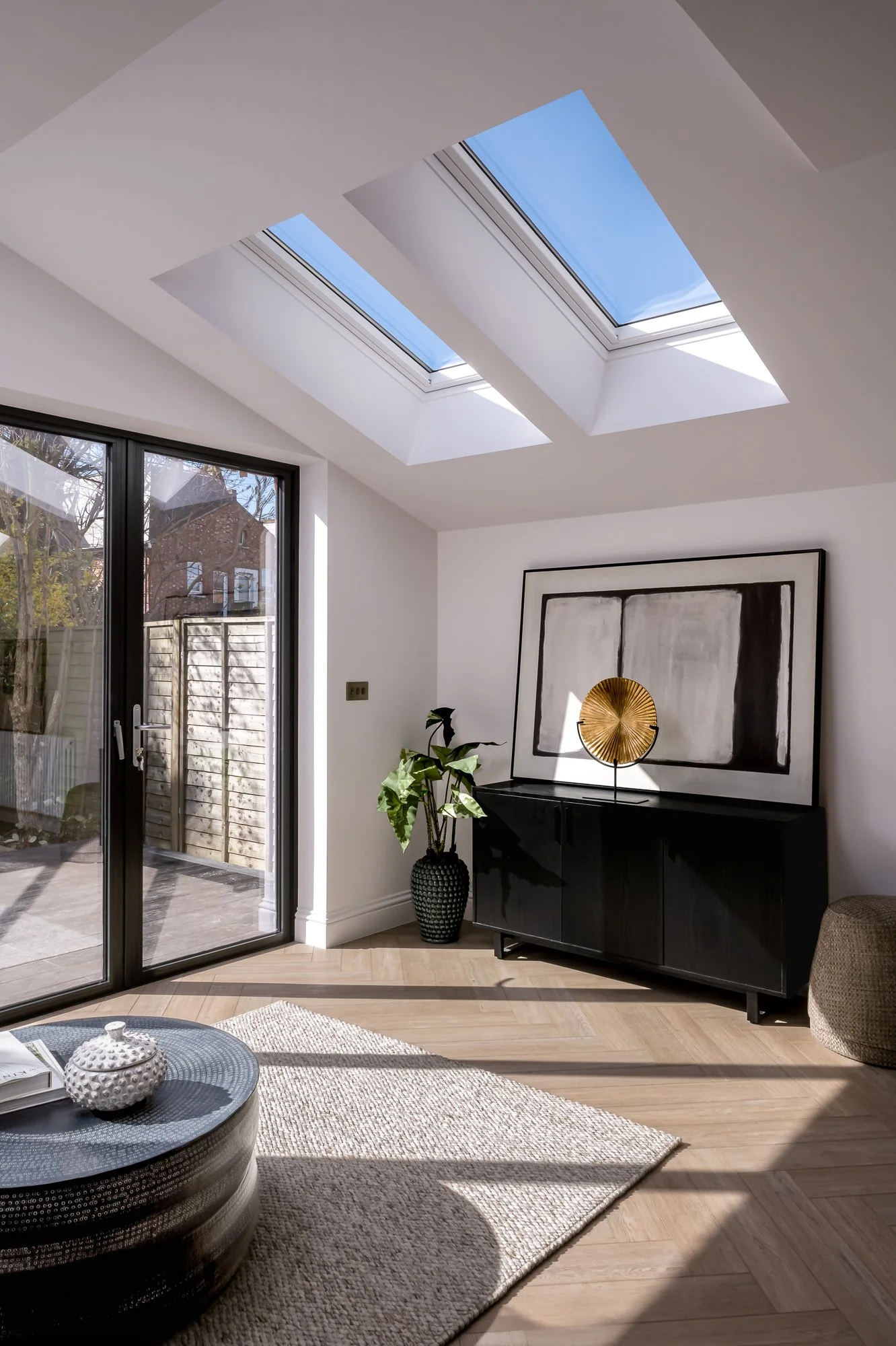  Interior architecture photograph of a residential extension with rooflights, large garden glazing, natural light, timber flooring and a bright open living space. Commercial image done for construction company in London.