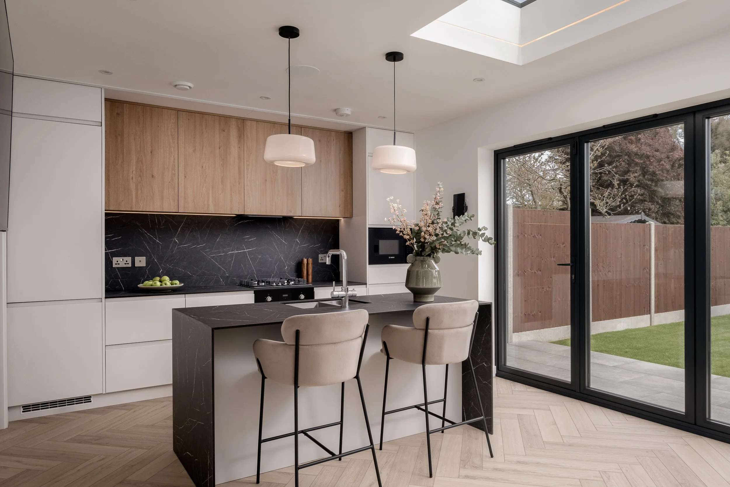Internal architectural perspective photograph of a contemporary residential rear extension, showcasing structural glazing and open-plan space planning. Shot for main contractors and development firms to document technical execution, featuring an over