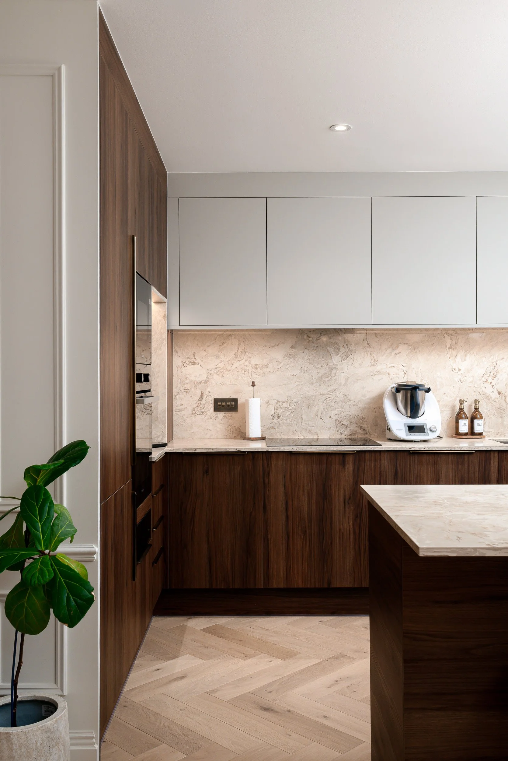 Detail architectural photograph capturing a premium kitchen island fit-out for a high-end residential development. Shot for main contractors and architectural firms to document precision craftsmanship, featuring a flawless mitered-edge quartz slab wa