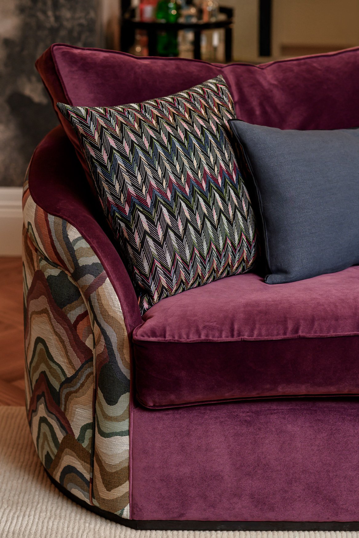Close-up of patterned cushion, upholstery and layered interior styling in a family lounge.