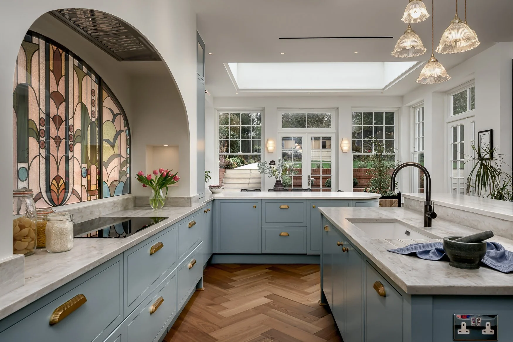 Colourful bespoke kitchen detail with stained glass, marble worktops and brass finishes.