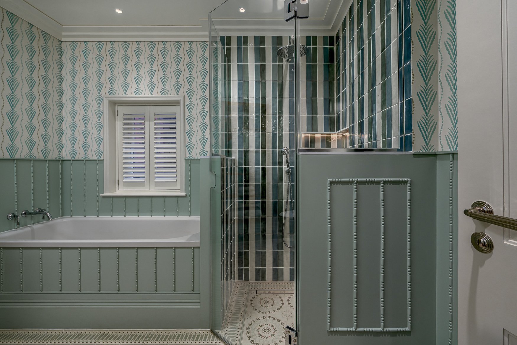 Green family bathroom with patterned wallpaper, panelled walls, bath and walk-in shower.