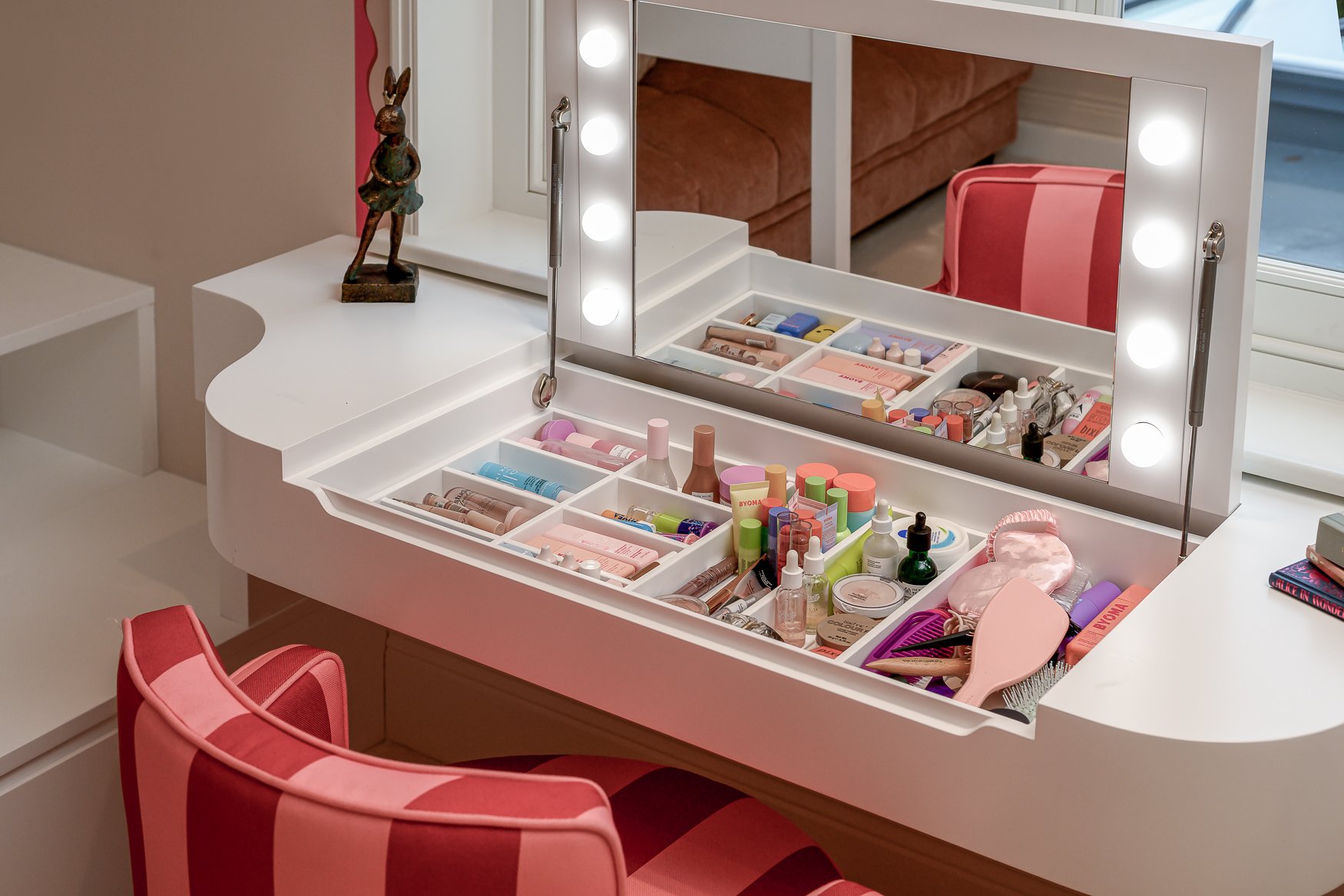 Children’s bedroom detail with playful pink furniture, patterned wallpaper and decorative styling.