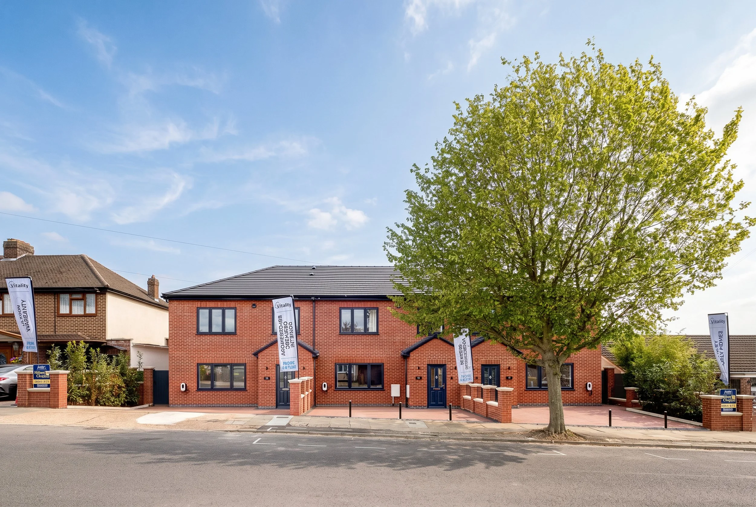 Front elevation architectural photograph of a modern multi-unit commercial residential development. Shot for main contractors and development firms to showcase external build quality, featuring symmetrical red facing brickwork masonry, crisp white st