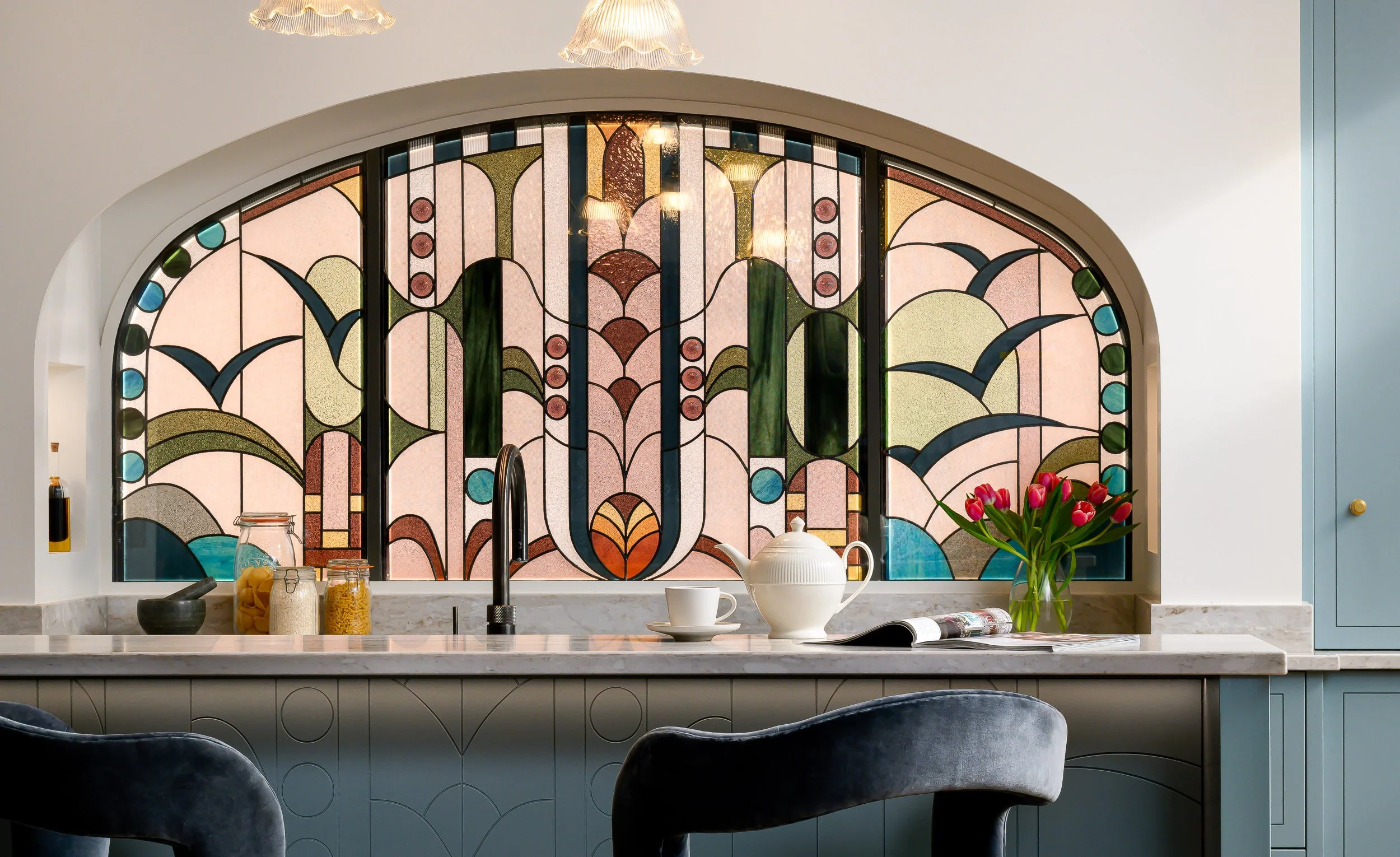 Bespoke kitchen interior photographed for an interior design project, featuring blue cabinetry, stained glass, marble surfaces and considered styling.