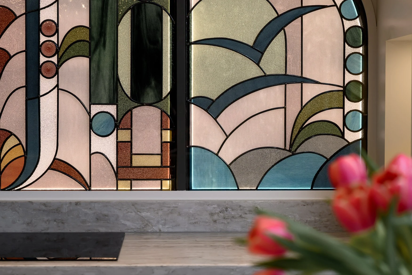 Kitchen detail with tulips, stained glass, brass handles and marble surfaces.