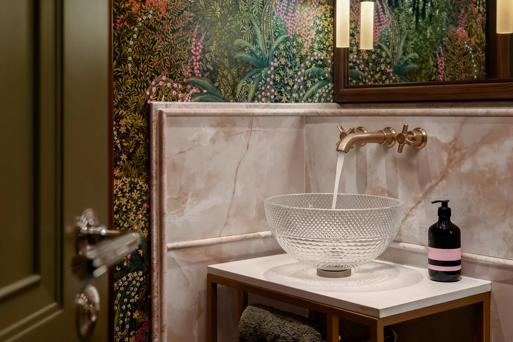 Family loo with a colourful, floral wallpaper, brass finishes, cristal sink