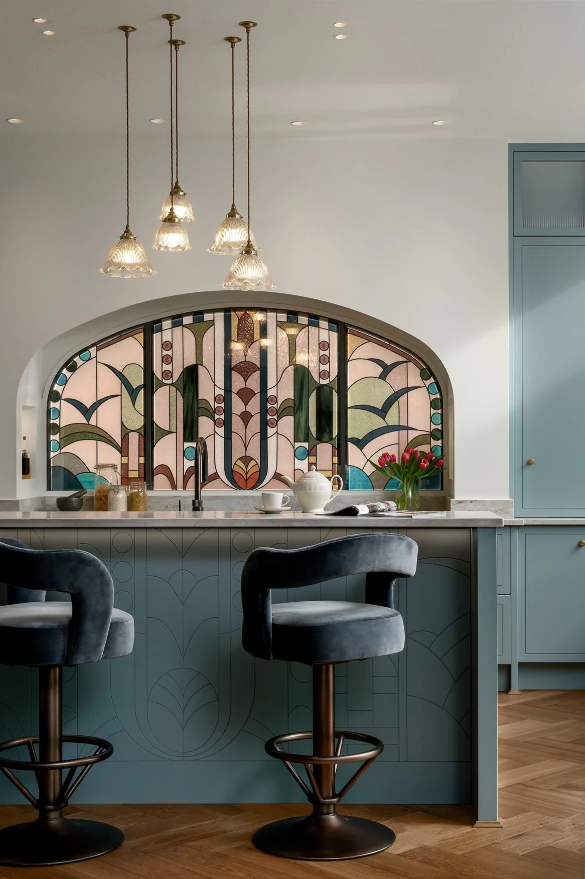 Colourful bespoke kitchen detail with stained glass, marble worktops and brass finishes.