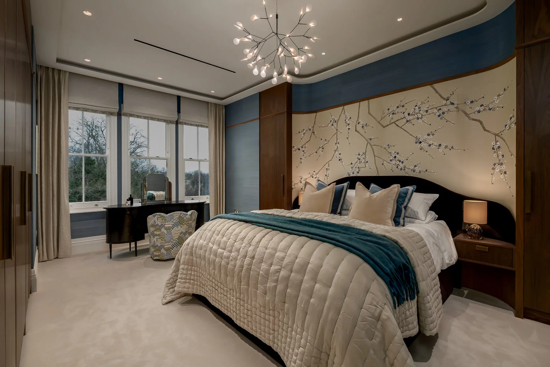 Bedroom with bespoke walnut joinery, blue grasscloth wall covering and upholstered headboard.