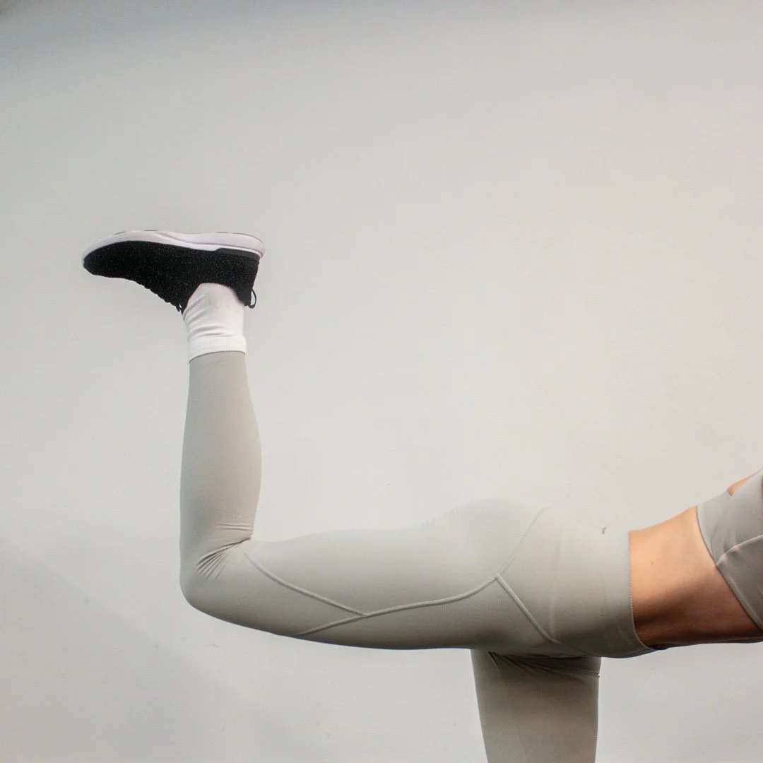 athletic leg with gray leggins black tennis shoe kicking upwards
