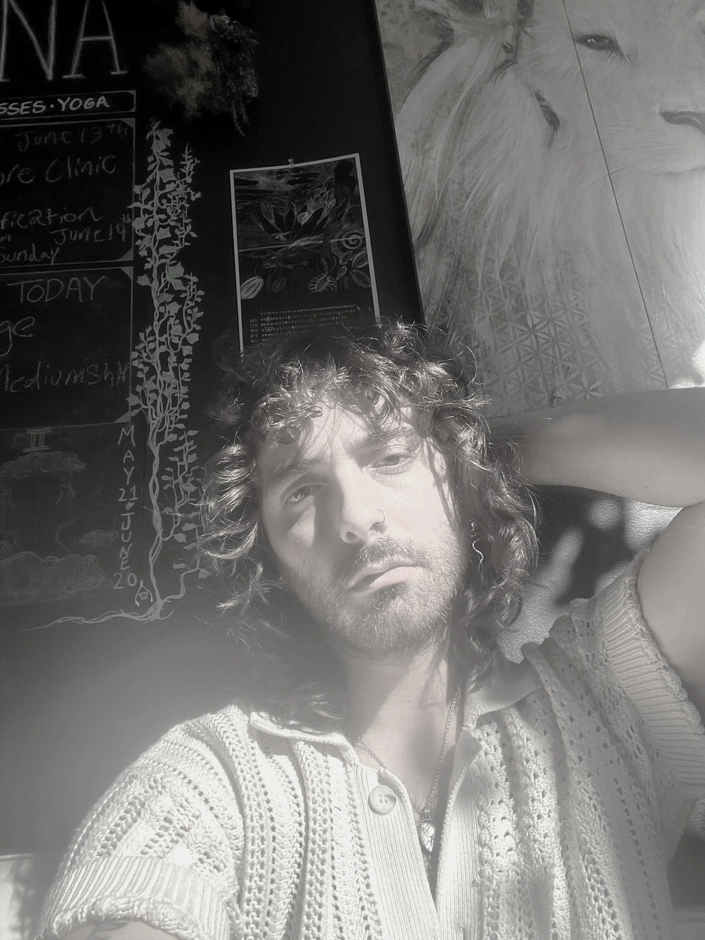 Black and white photo of a person with long, wavy hair, wearing a dark top and jewelry, holding cash in front of them, with a serious expression.