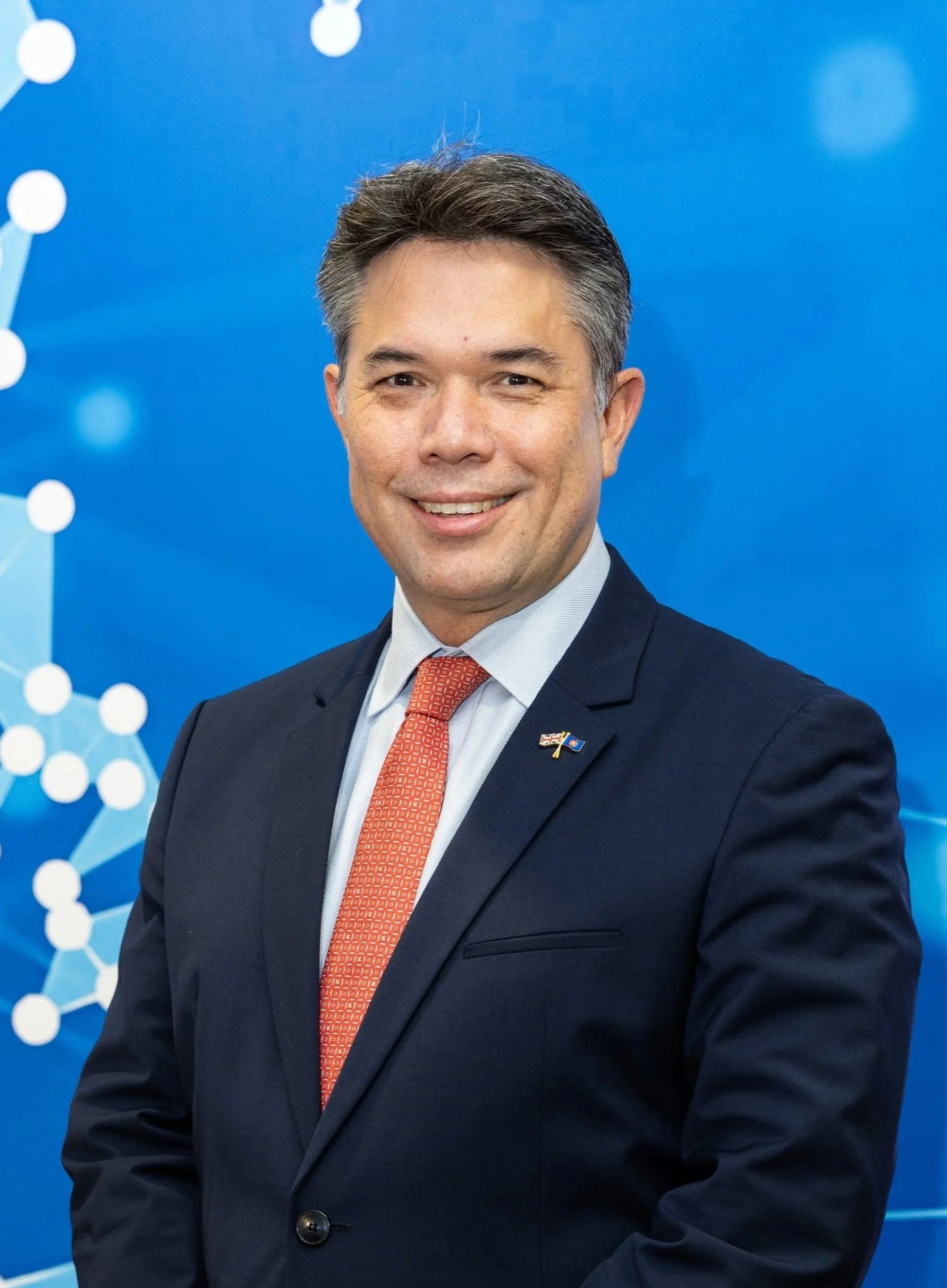 Smiling man in a suit and tie against a white background.