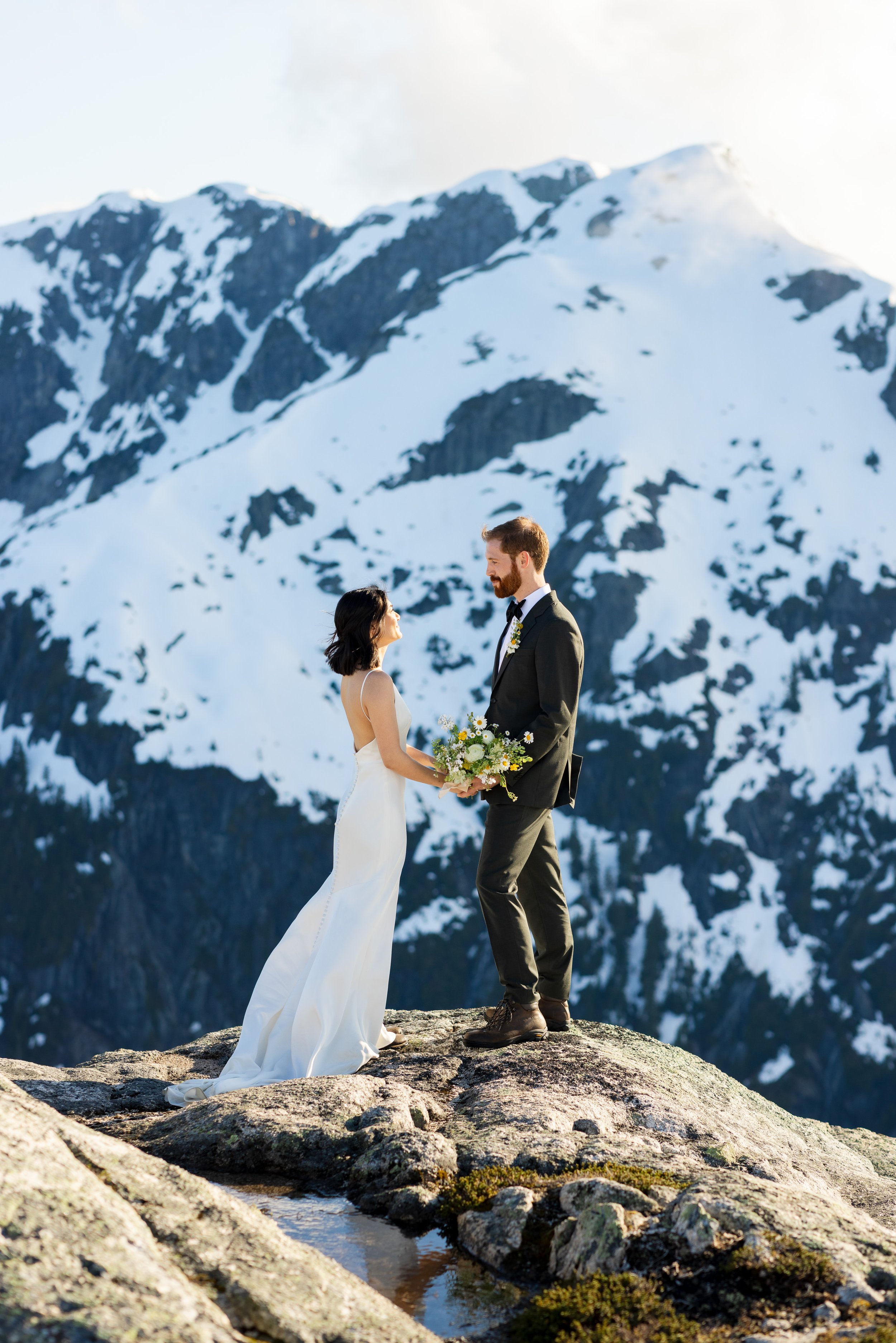 A couple looking at each other with a snowy mountain in the background.