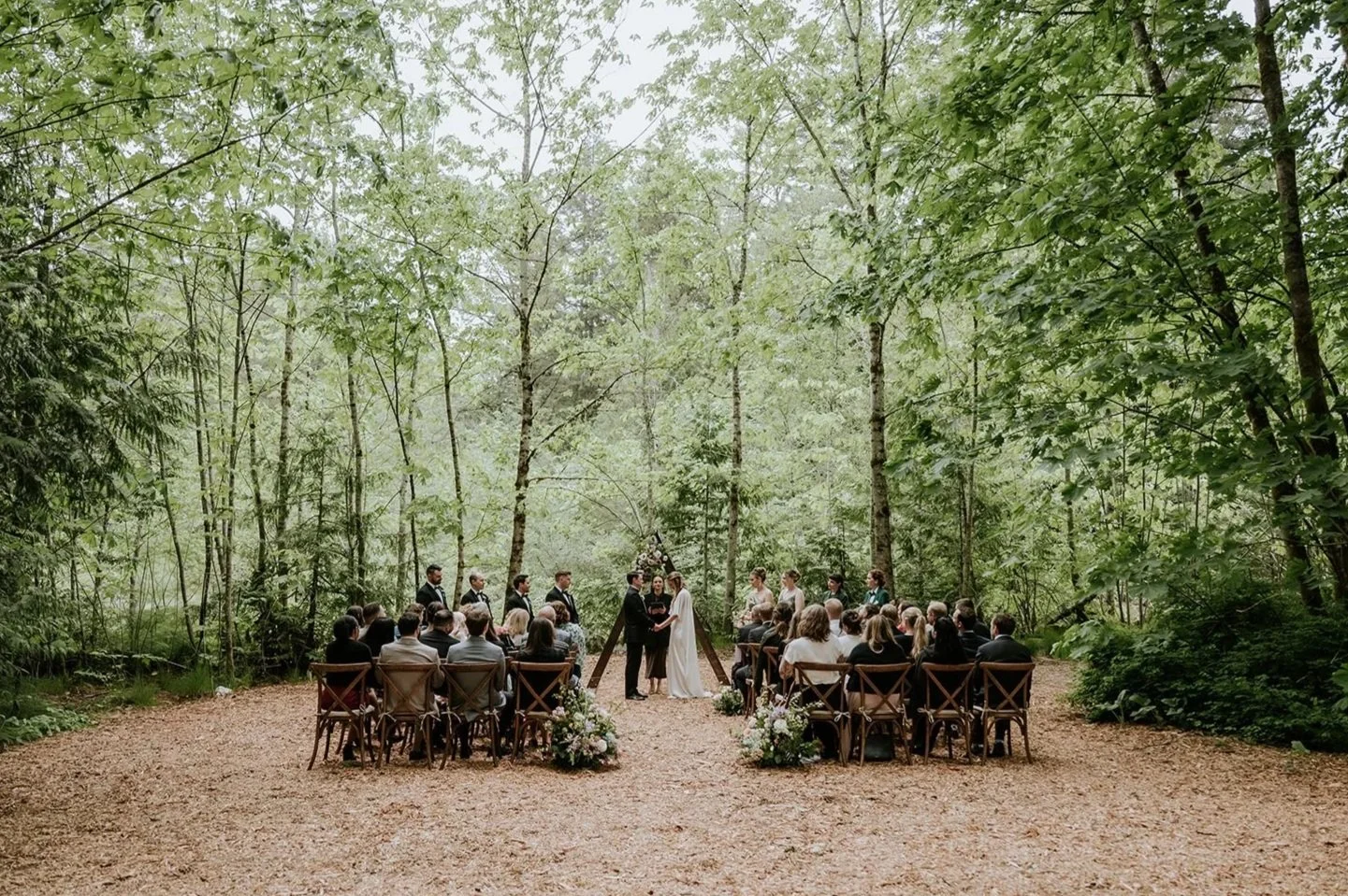 A wedding in the forest at Sunwolf BC, with the guests seated and the bride and groom at the front