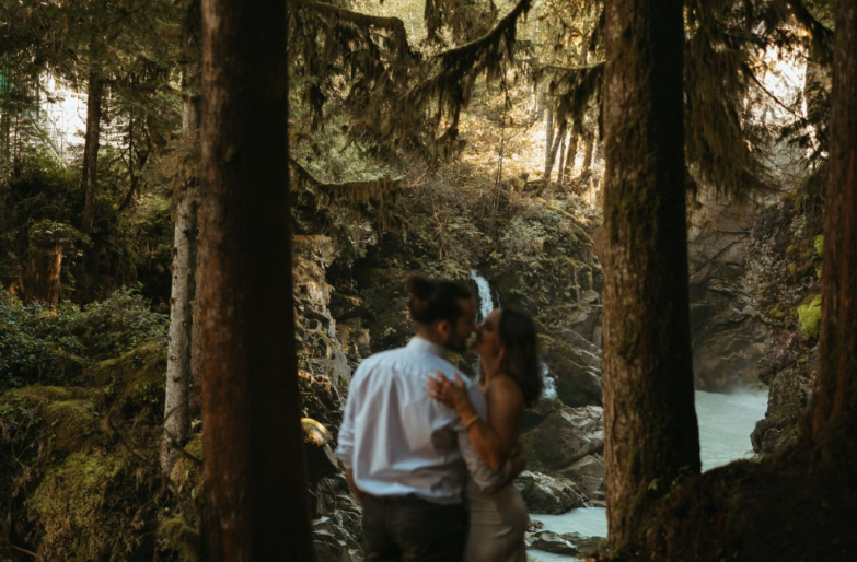 A couple kissing in front of a waterfall