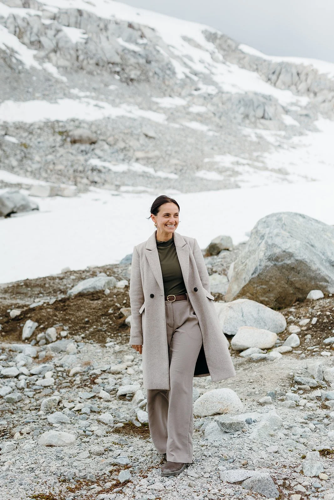 An elopement planner walking in the alpine, smiling at her couple who are not in the photo