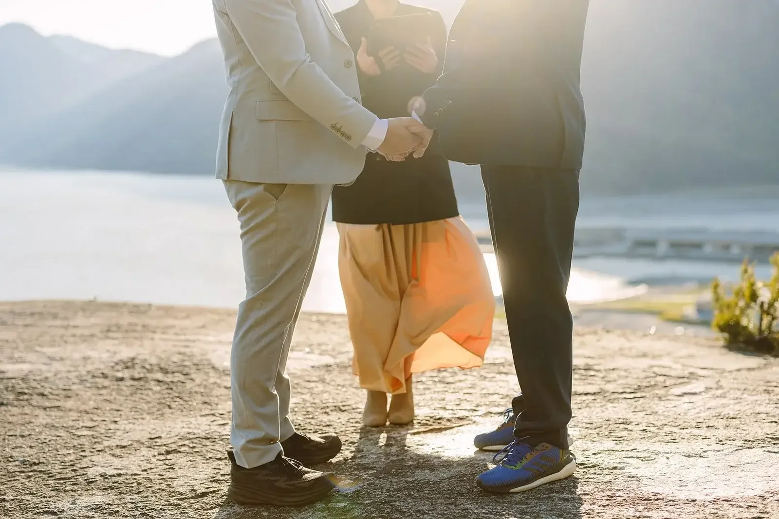 Two grooms getting married in front of a beautiful lake landscape
