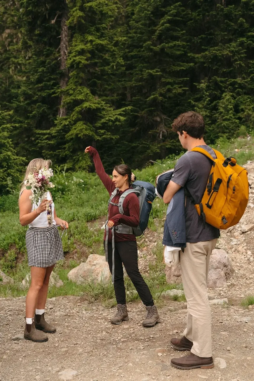 jude and her couple stand with backpacks as they prepare for the wedding ceremony