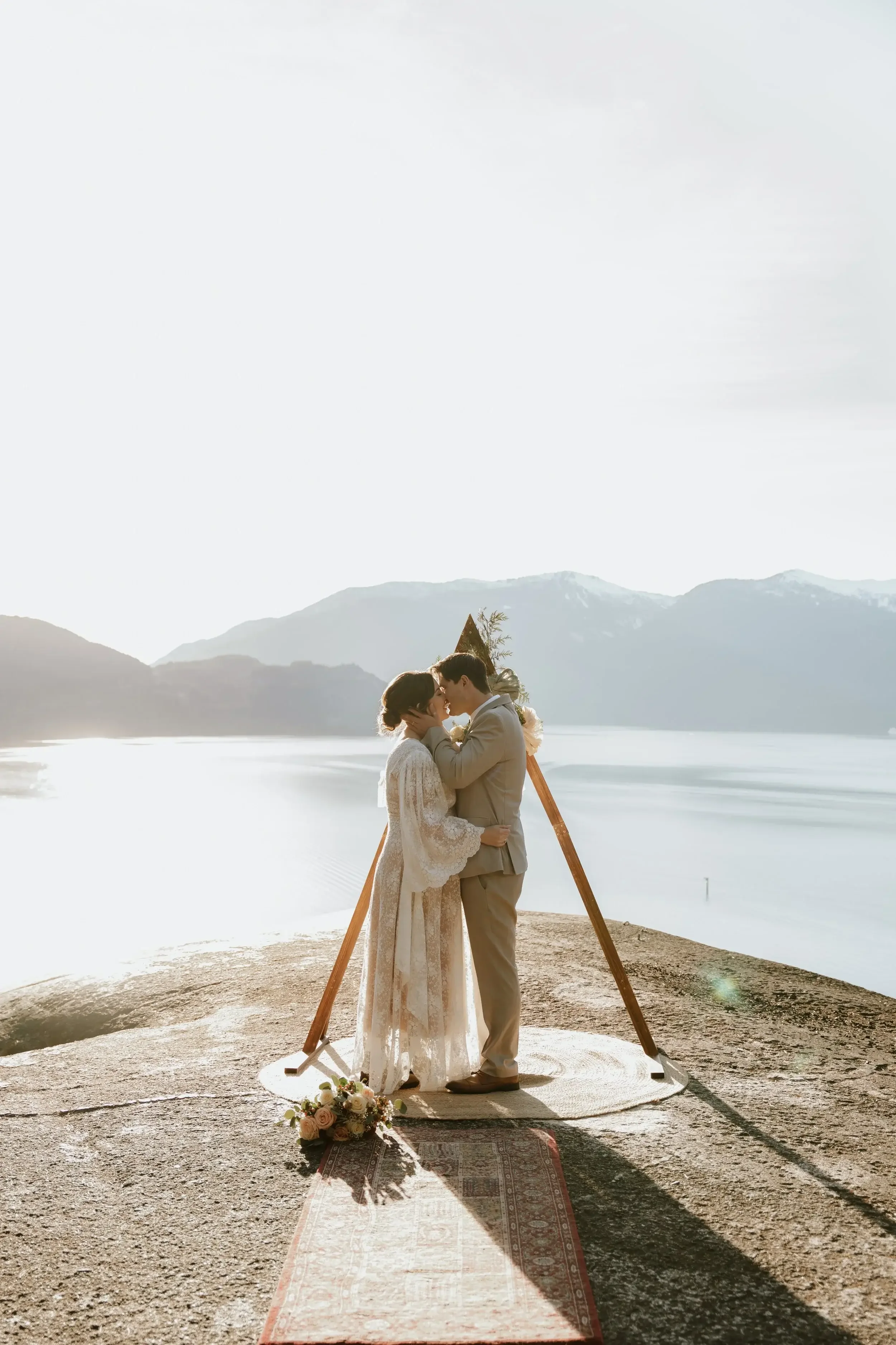 bride and groom kiss with sea to sky view at microwedding