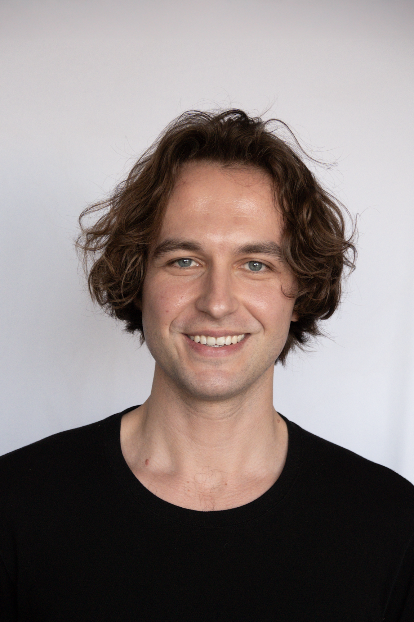 Headshot of Will Brennan wearing a black shirt against a plain light background.