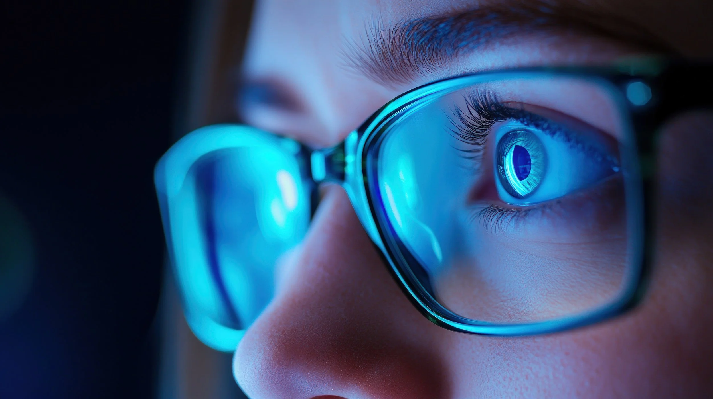 Close-up of a person's eye wearing glasses, with a reflection of a circular pattern in the eye and blue lighting | Dr. Robert Meade | Public Speaker & Vision Consultant | Presentations about Eyes and Vision