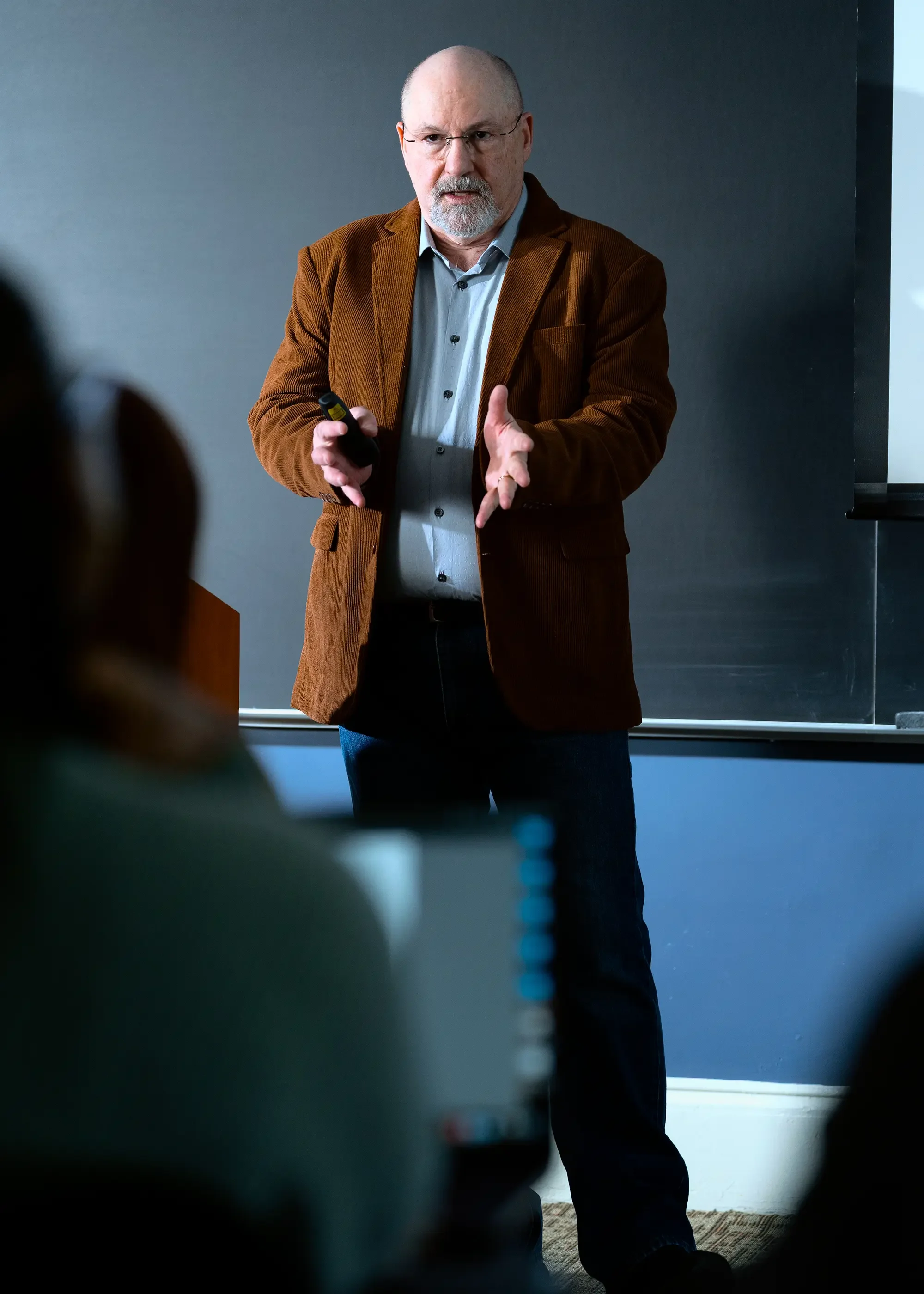 A middle-aged man with glasses, a beard, and a bald head giving a presentation in a classroom or conference room | Dr. Robert Meade | Public Speaker & Vision Consultant | Presentations about Eyes and Vision