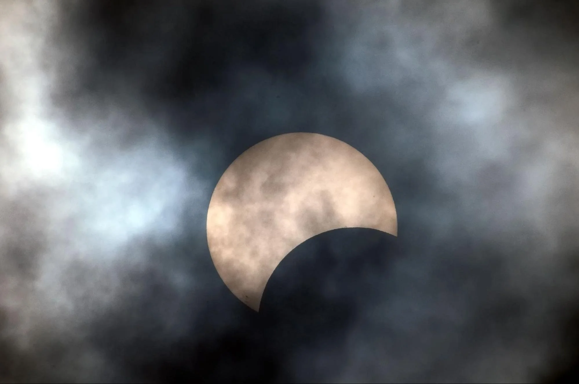 image of a partial solar eclipse behind clouds