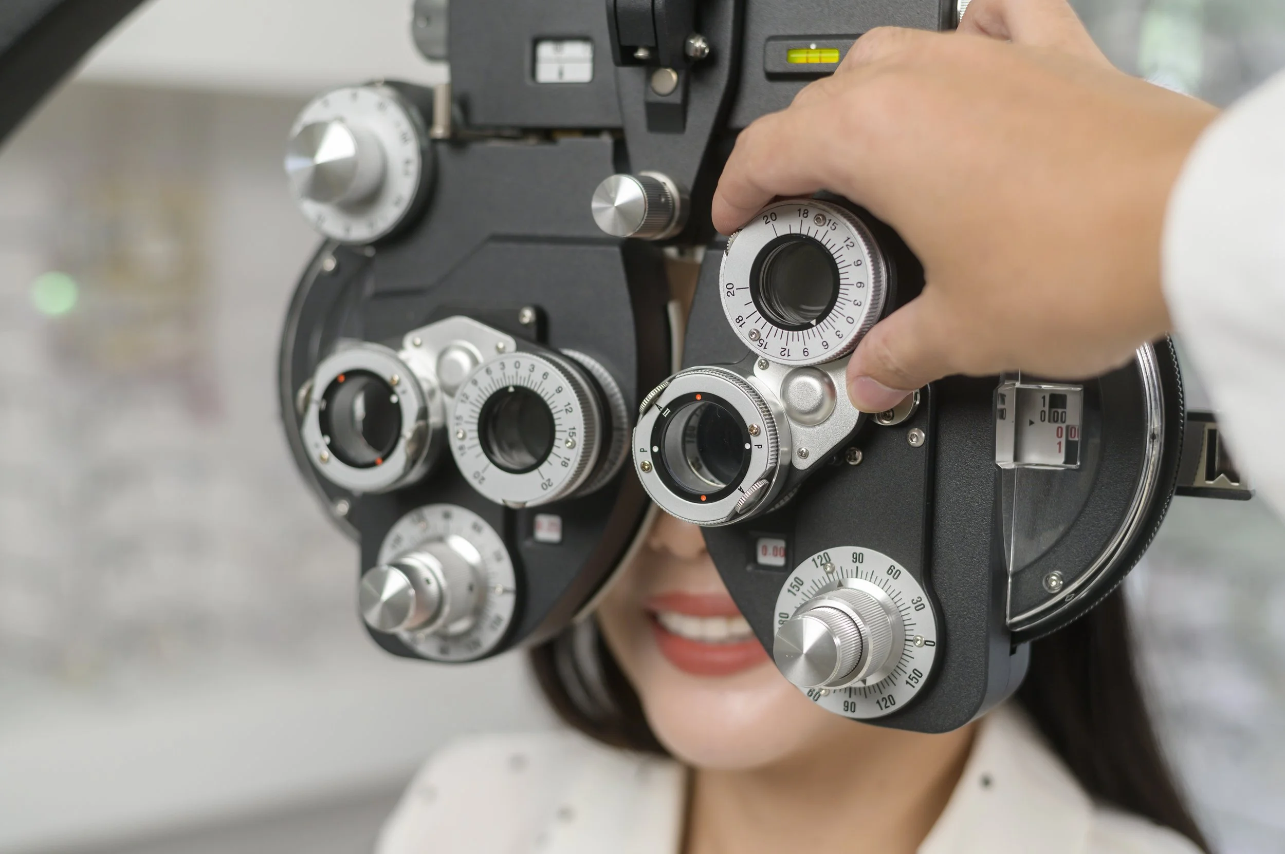 A woman looking through a phoropter during an eye exam | Dr. Robert Meade | Public Speaker & Vision Consultant | Presentations about Eyes and Vision