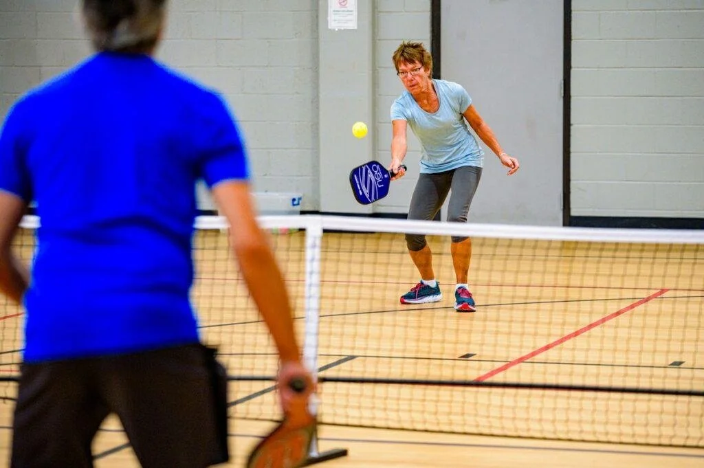 Woman hitting pickleball over the net with a paddle