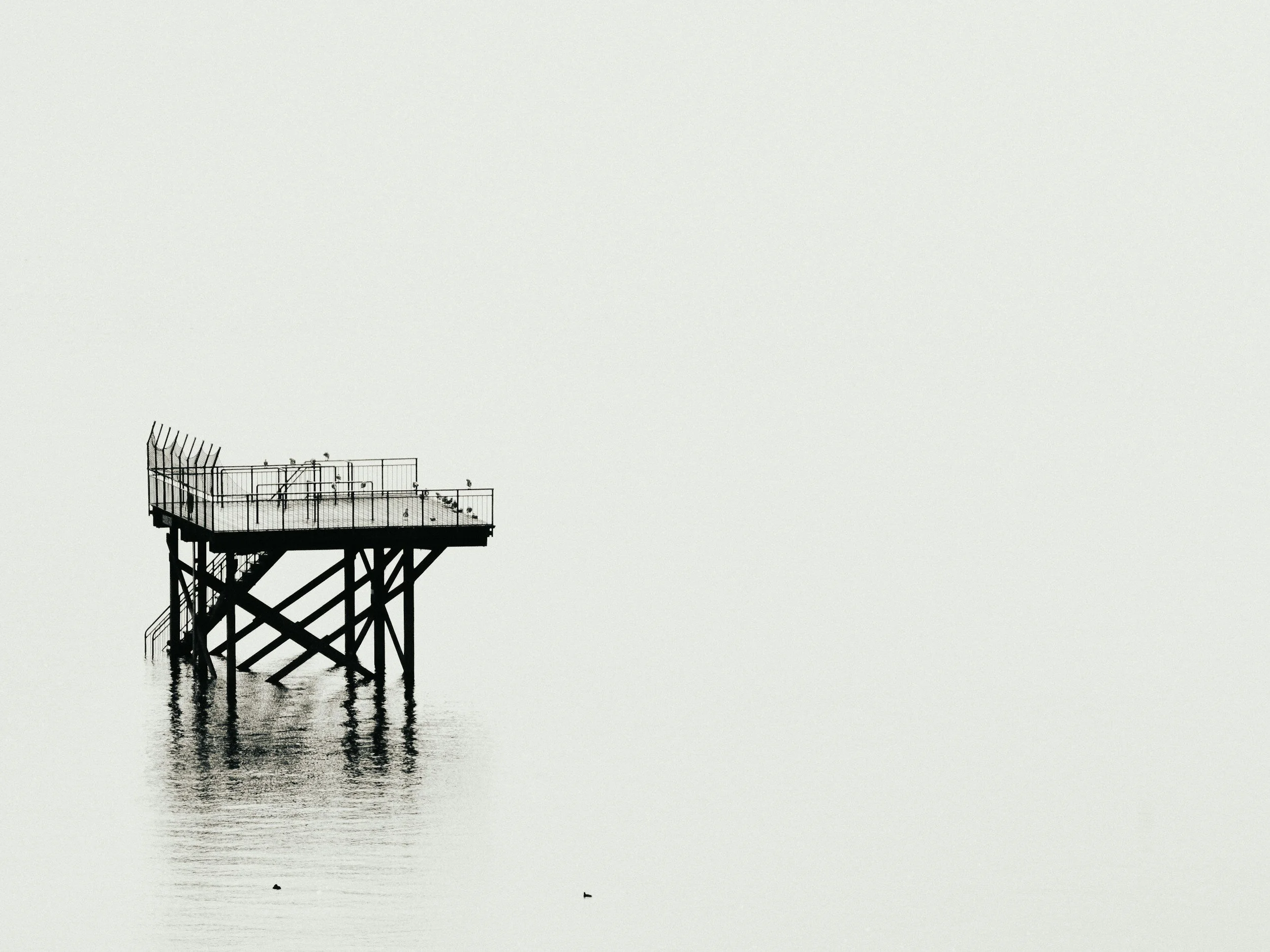 A lone jetty structure standing in calm, pale water
