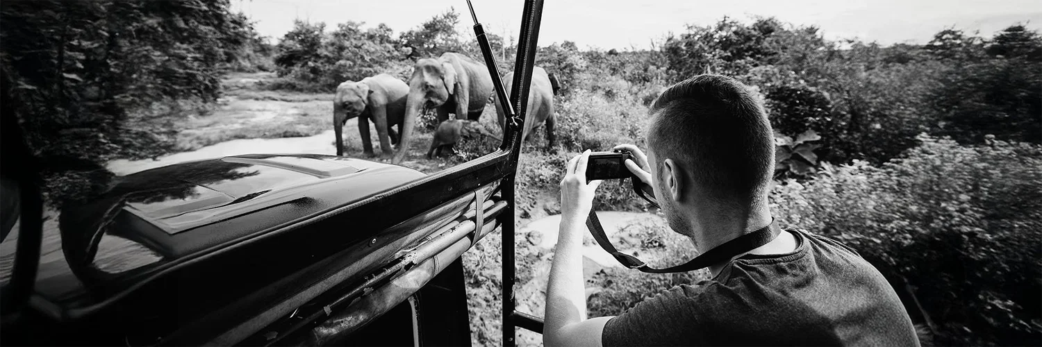 A photographer framing a shot from a vehicle on location