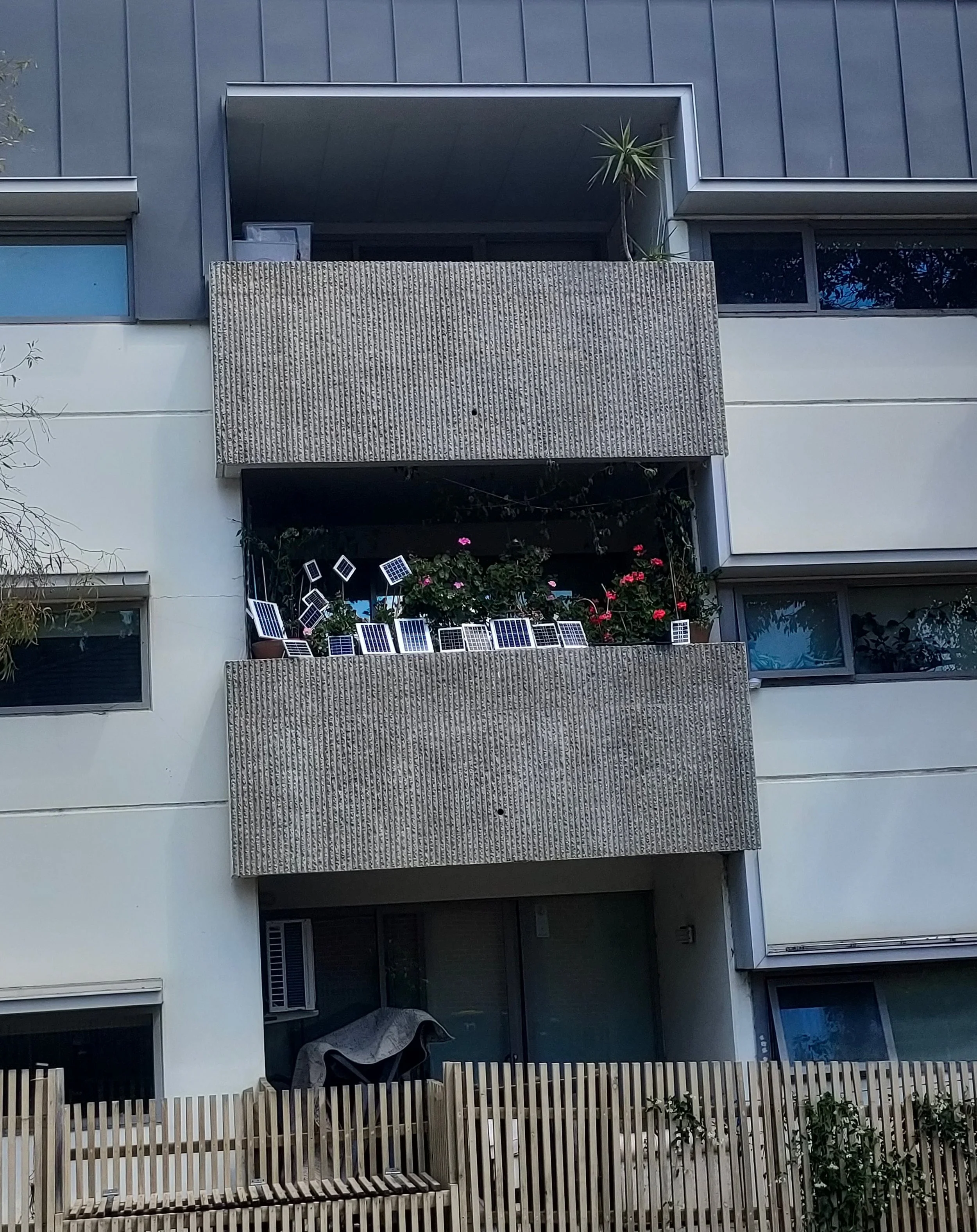 Lots of mini solar panels on a small, concrete apartment balcony.