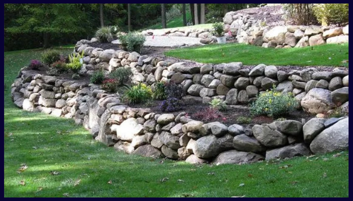 Tiered natural rock retaining wall on a sloped property in Albury-Wodonga with garden landscaping
